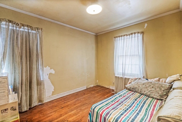 bedroom featuring ornamental molding, baseboards, and wood finished floors