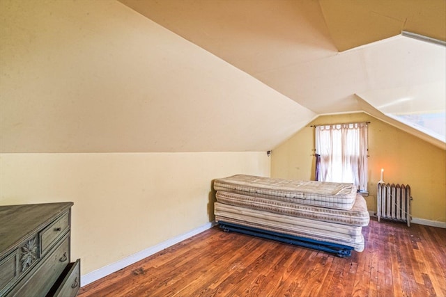 bedroom featuring hardwood / wood-style flooring, radiator, baseboards, and lofted ceiling