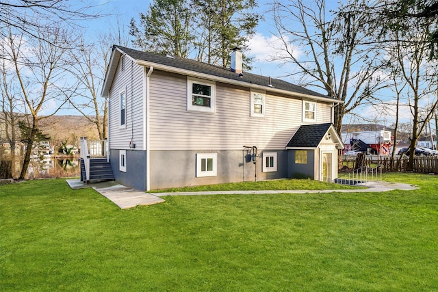 rear view of property with a yard, fence, and a chimney