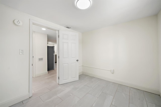 unfurnished room with baseboards and visible vents