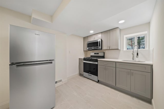 kitchen featuring visible vents, gray cabinetry, a sink, light countertops, and appliances with stainless steel finishes