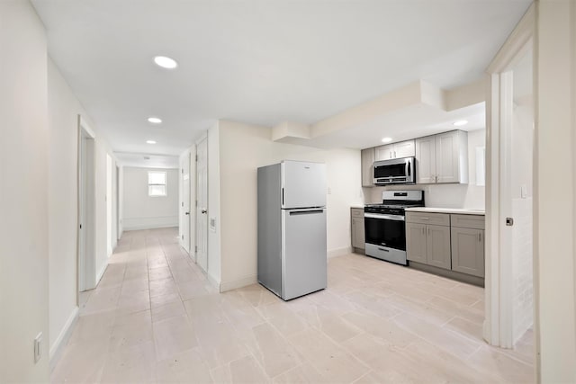 kitchen with gray cabinetry, recessed lighting, appliances with stainless steel finishes, light countertops, and baseboards