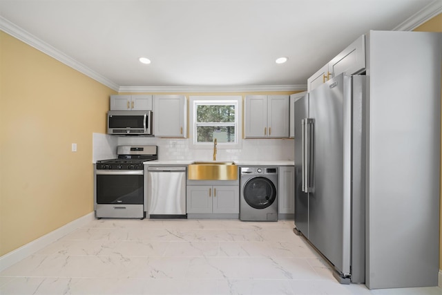 kitchen with marble finish floor, ornamental molding, a sink, appliances with stainless steel finishes, and washer / dryer