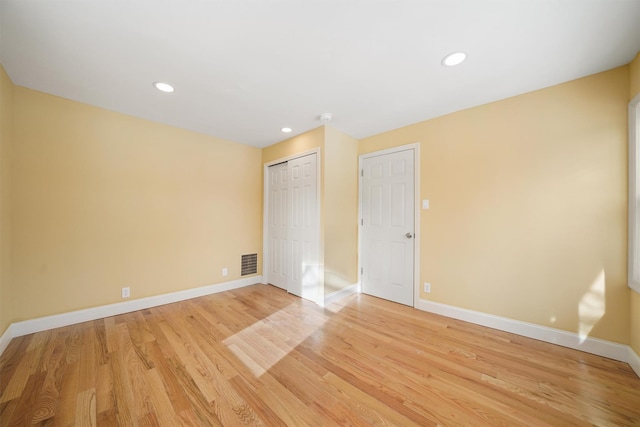 unfurnished room with recessed lighting, visible vents, light wood-style flooring, and baseboards