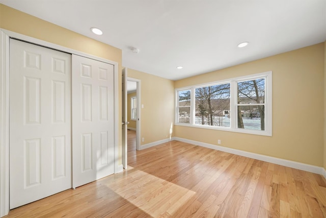 unfurnished bedroom featuring light wood-style flooring, recessed lighting, baseboards, and a closet