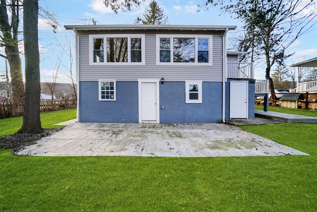 rear view of house featuring a yard, a patio, fence, and stucco siding