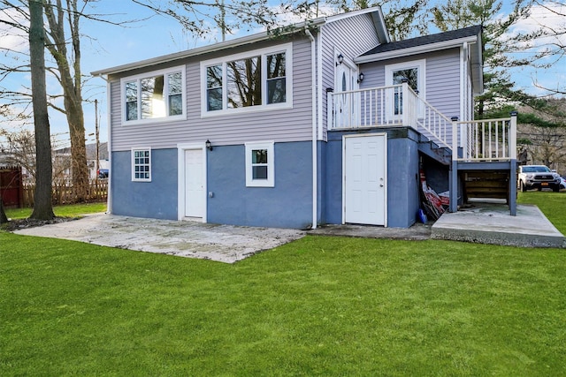 rear view of property featuring stucco siding, a lawn, fence, stairs, and a patio area