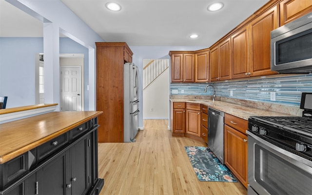 kitchen featuring a sink, brown cabinets, appliances with stainless steel finishes, and light wood-style flooring