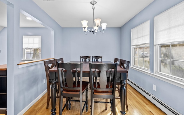 dining area with a wealth of natural light, a chandelier, baseboard heating, and wood finished floors