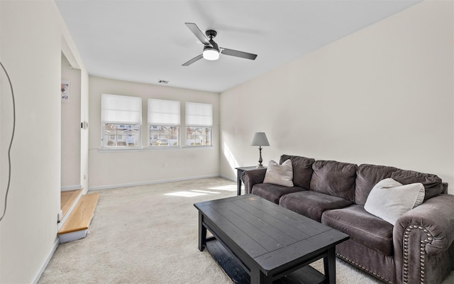 living area with visible vents, light colored carpet, baseboards, and ceiling fan