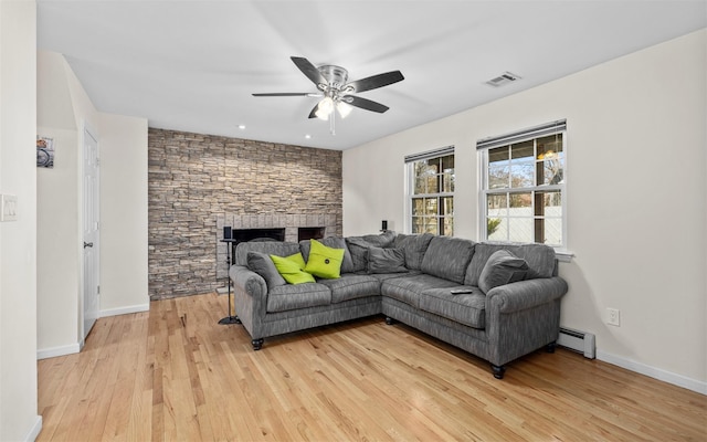 living room with visible vents, baseboards, light wood-style flooring, a fireplace, and a baseboard radiator