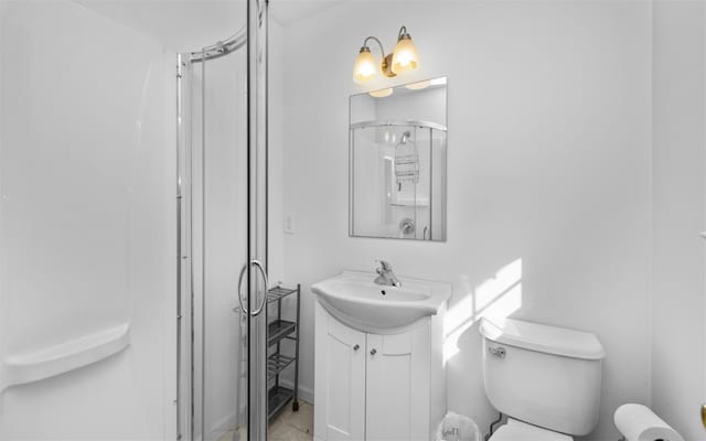 bathroom with tile patterned flooring, vanity, a shower stall, and toilet