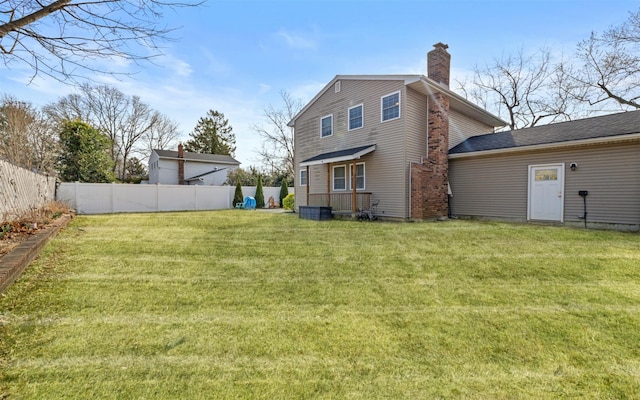 back of house with a yard, a fenced backyard, and a chimney