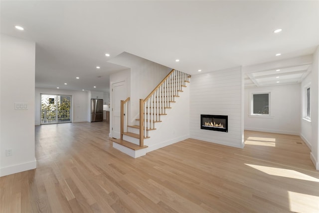 unfurnished living room featuring recessed lighting, baseboards, a fireplace, and light wood finished floors