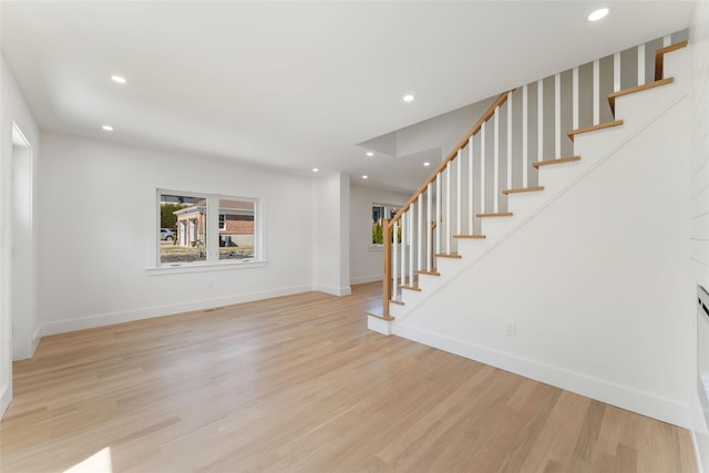 unfurnished living room featuring recessed lighting, stairs, light wood-type flooring, and baseboards