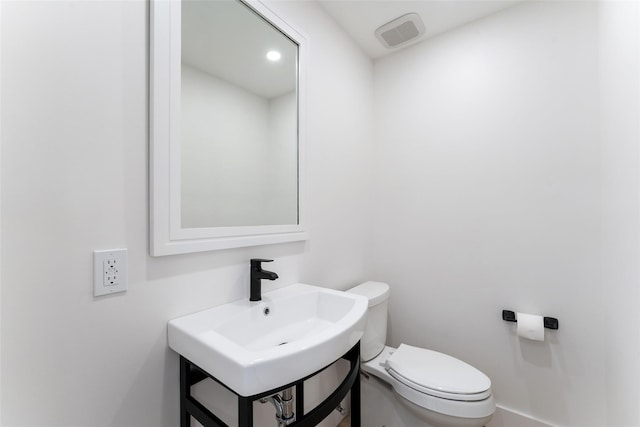 half bath with visible vents, toilet, and vanity