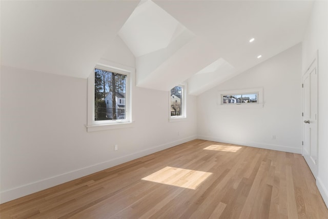 additional living space with recessed lighting, light wood-type flooring, baseboards, and lofted ceiling with skylight