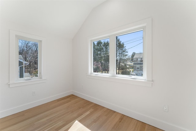 empty room featuring baseboards, lofted ceiling, and light wood finished floors