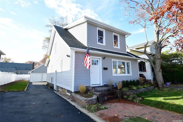 view of front of house featuring an outbuilding, driveway, fence, a shingled roof, and a garage