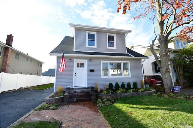 bungalow-style home featuring a front lawn and fence