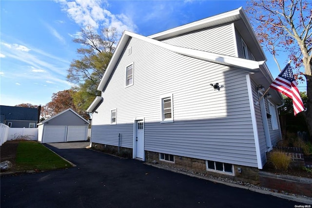 view of property exterior featuring a garage, an outdoor structure, and fence