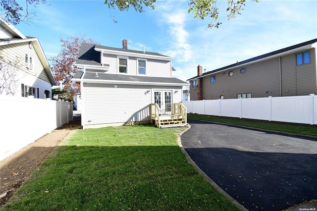 rear view of house featuring french doors, a yard, a chimney, and fence