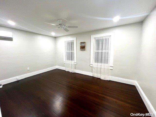 unfurnished room with baseboards, dark wood-style flooring, and ceiling fan