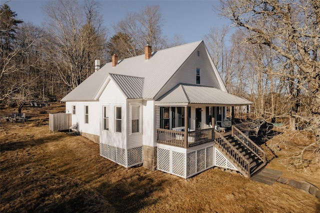 rear view of property with a chimney, covered porch, and metal roof