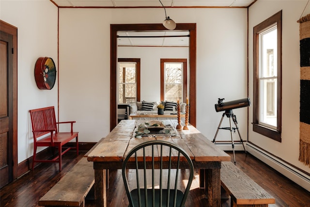 dining area with dark wood finished floors, baseboard heating, crown molding, and baseboards