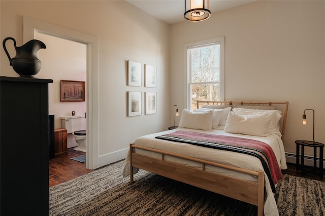 bedroom with a baseboard heating unit, baseboards, and wood finished floors