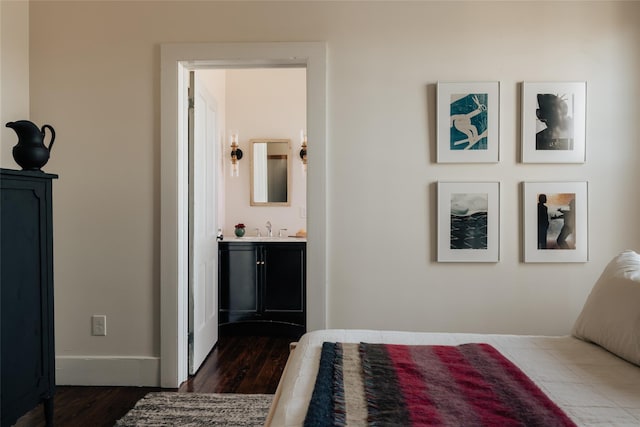 bedroom featuring a sink, ensuite bath, and dark wood finished floors