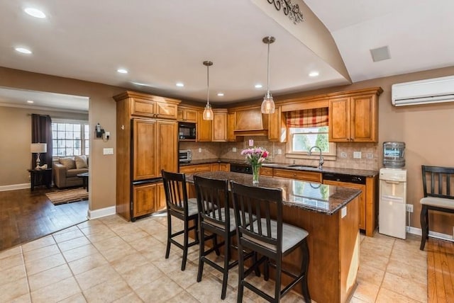 kitchen with black microwave, decorative backsplash, brown cabinets, a wall mounted AC, and a sink