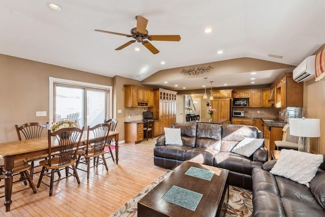 living area with a ceiling fan, vaulted ceiling, an AC wall unit, and light wood-style floors