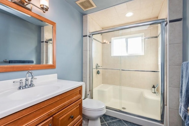 full bath featuring a shower with shower door, visible vents, toilet, tile patterned flooring, and vanity