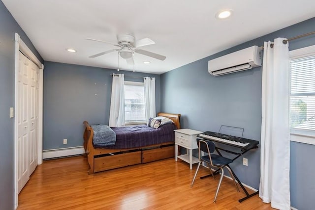 bedroom with a baseboard heating unit, baseboards, light wood-type flooring, recessed lighting, and a wall mounted AC