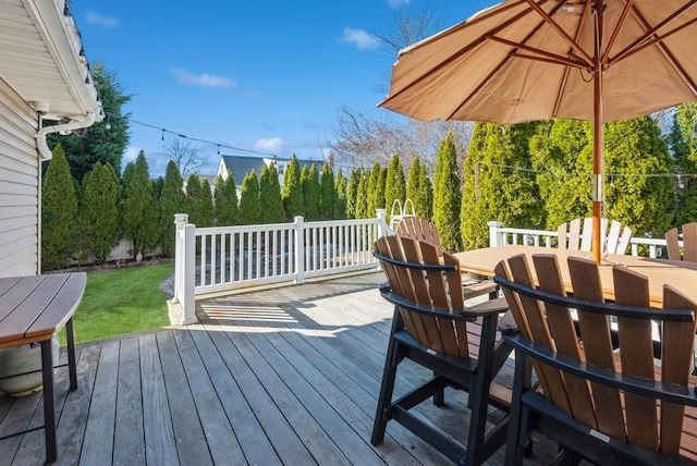 wooden deck featuring outdoor dining space and a yard