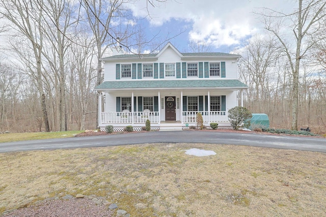 view of front of home featuring a chimney, roof with shingles, a porch, and a front lawn