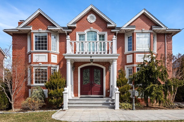 view of front facade with brick siding, french doors, and a balcony