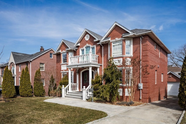 view of front of house with an outbuilding, a balcony, brick siding, and a front yard