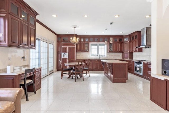 kitchen featuring a notable chandelier, wall chimney exhaust hood, light countertops, stainless steel oven, and hanging light fixtures