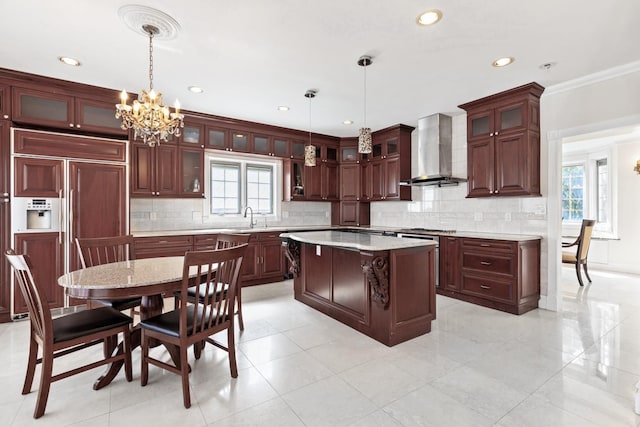 kitchen with decorative light fixtures, a kitchen island, wall chimney exhaust hood, paneled built in refrigerator, and a chandelier