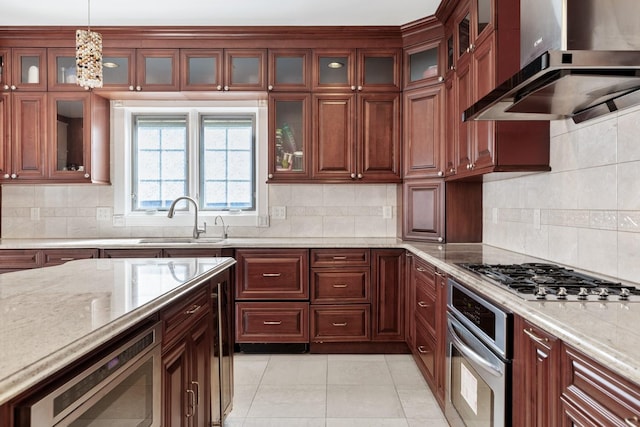 kitchen featuring a sink, backsplash, appliances with stainless steel finishes, extractor fan, and hanging light fixtures