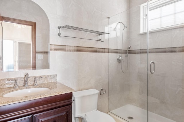 full bath with vanity, a shower stall, toilet, and tile walls