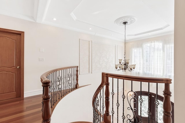 interior space featuring an upstairs landing, a notable chandelier, ornamental molding, wood finished floors, and baseboards