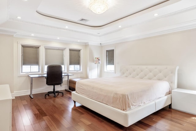 bedroom featuring visible vents, baseboards, a tray ceiling, and wood finished floors