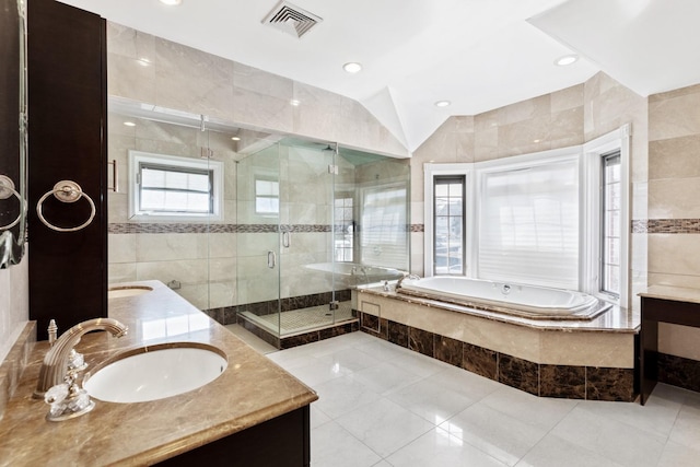 bathroom featuring double vanity, a stall shower, a sink, a garden tub, and tile walls