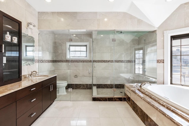 bathroom featuring toilet, vanity, lofted ceiling, a stall shower, and tile walls