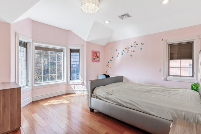 bedroom with visible vents, multiple windows, light wood-type flooring, and lofted ceiling