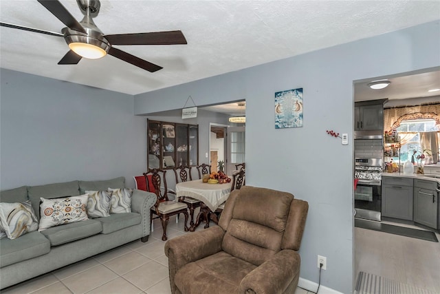 living room with ceiling fan, light tile patterned floors, and a textured ceiling