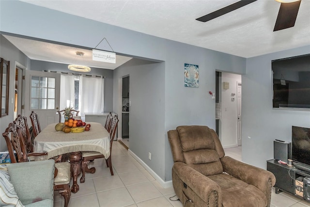 dining space featuring light tile patterned flooring, a ceiling fan, and baseboards